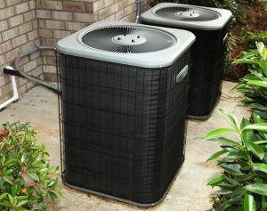 two outdoor units of an air conditioner sitting on a concrete slab